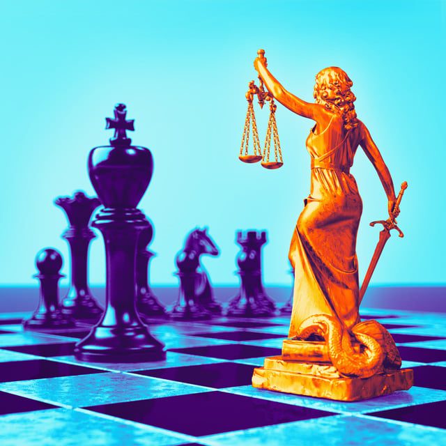 Image of justice, with a statue holding two scales next to a chess board