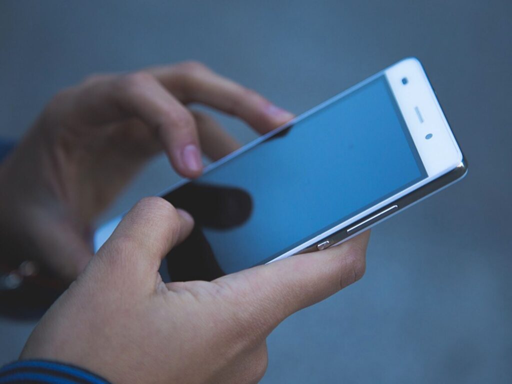 Close-up of hands using a white smartphone