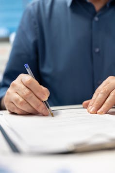 Close up of man signing a document