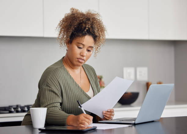 Shot of a woman filling in some paperwork at home Life can wait, get distracted! small business health insurance stock pictures, royalty-free photos & images