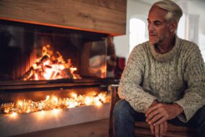 Man sitting by fireplace