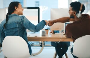 Rearview shot of two young designers giving each other a fist bump in an office