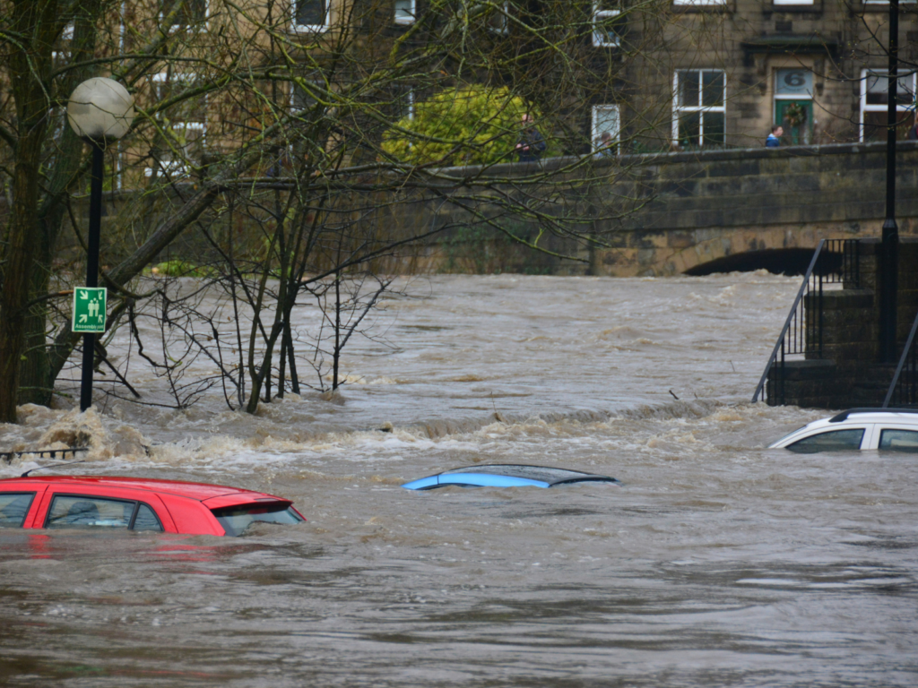 Three cars submerged under water on flooded street