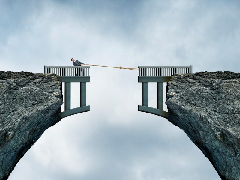 Man in suit using rope to close gap in a bridge. Represents insurance protection gap.