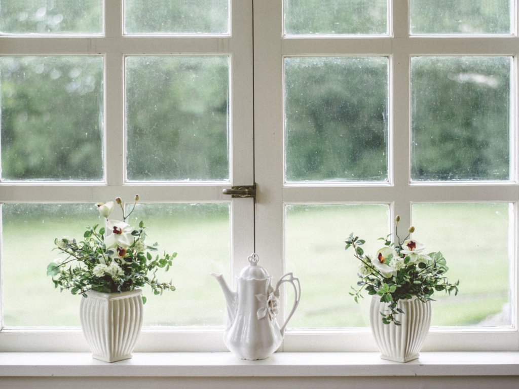 Windows with jug and flowers on windowsill 