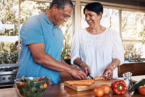 A mature couple cuts vegetables for a healthy salad in the kitchen.