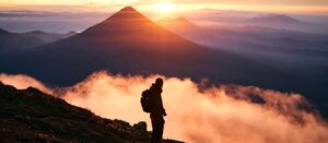 Man looking out at misty mountain sunset