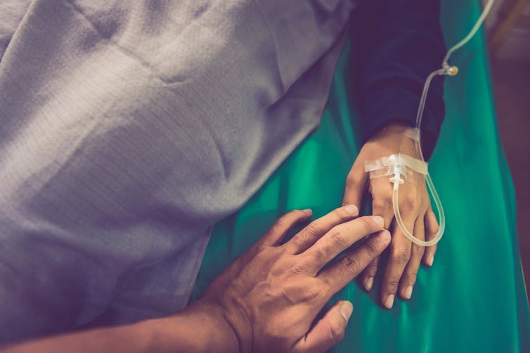 Someone touching the hand of a person in hospital.