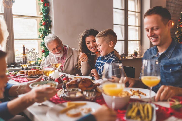 A happy family eats Christmas lunch around the table.