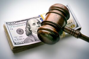 A photo of a gavel resting on a stack of money.