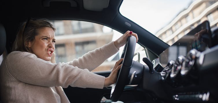 A woman beeps her horn and shouts at another driver.