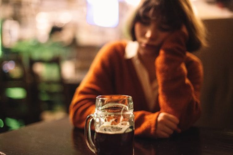 A woman in a pub with a glass of beer.