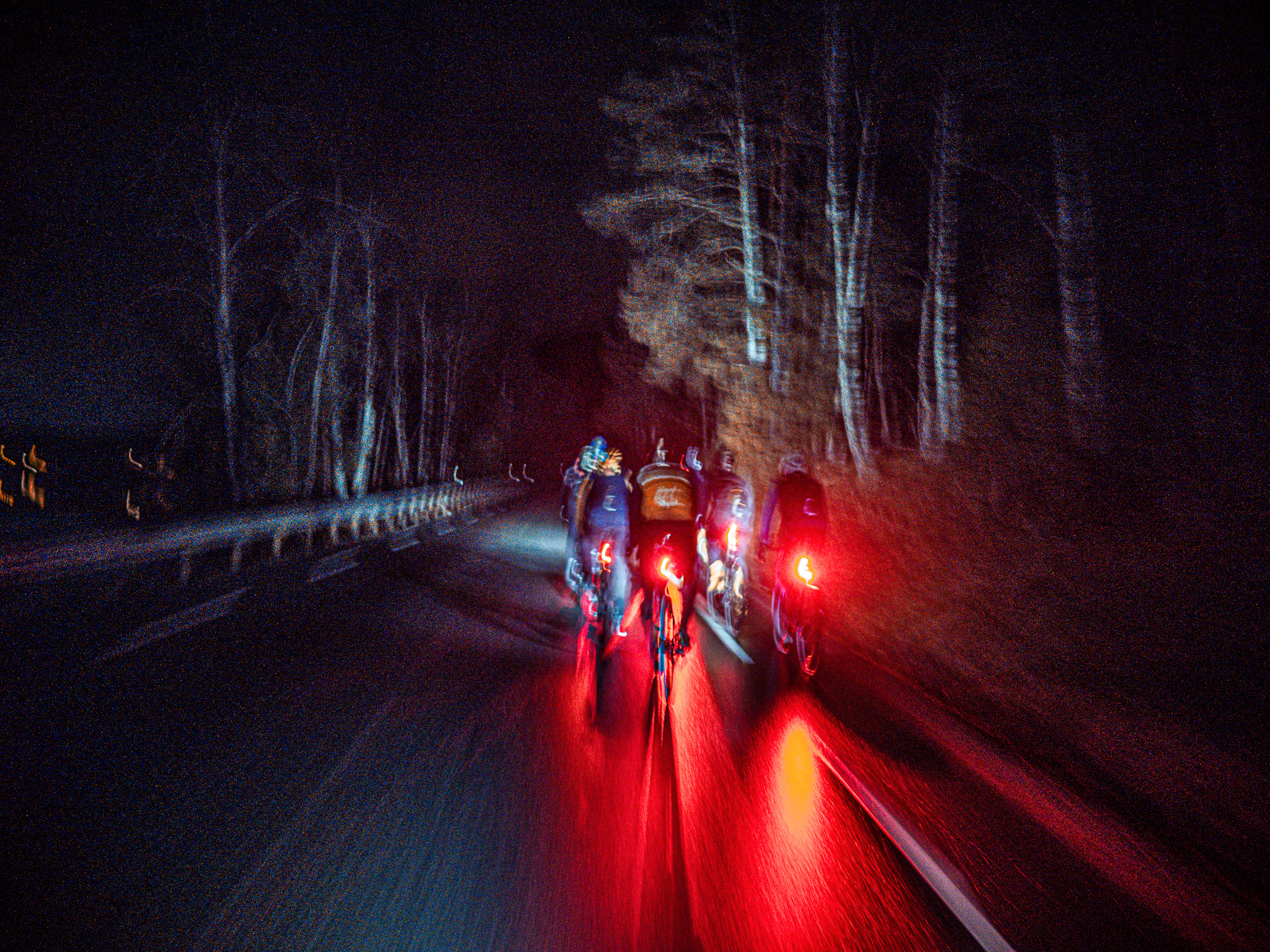 A group of cyclists riding in the dark