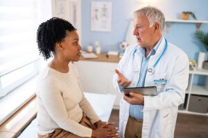 A woman talks to her male physician in the exam room