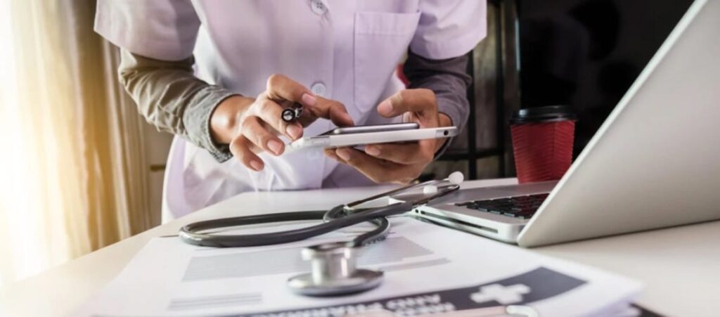 female physician in pink scrubs works on phone