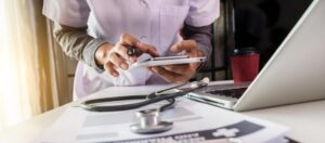 female physician in pink scrubs works on phone